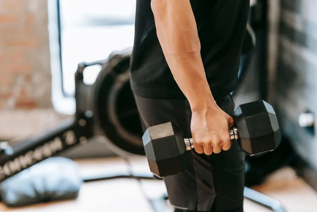 Dettaglio di un atleta che impugna un manubrio durante un allenamento di forza in palestra